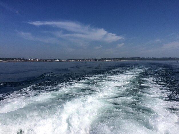 Vista de um barco no mar para a cidade velha na costa no horizonte ondas espumosas espalhadas de