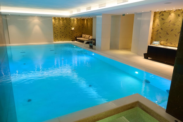 Vista de um belo e espaçoso interior com piscina térmica coberta com cascata em uma luxuosa área de estar de um resort spa de bem-estar
