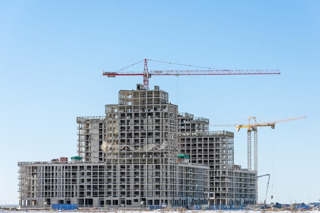 Vista de um complexo residencial em construção com guindastes altos. edifício em larga escala da cidade