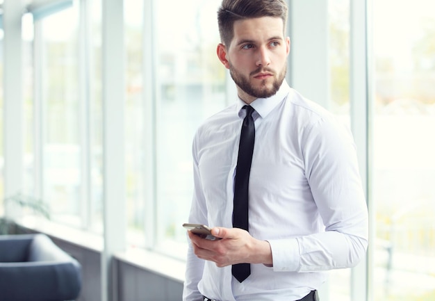 Foto vista de um homem de negócios atraente jovem usando smartphone