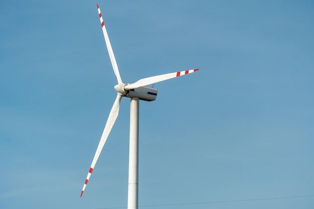 Vista de um moinho de vento moderno contra um céu azul As lâminas brancas da turbina eólica fecham Fonte de energia renovável Produção de eletricidade barata e segura