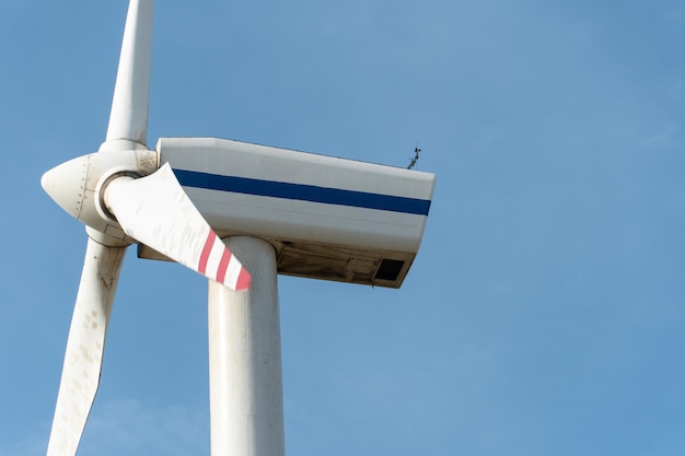 Vista de um moinho de vento moderno contra um céu azul As lâminas brancas da turbina eólica fecham Fonte de energia renovável Produção de eletricidade barata e segura