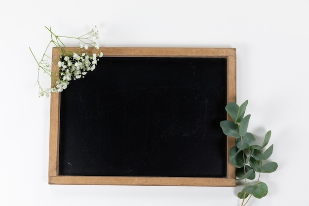 Vista de um quadro negro cercado por flores sobre fundo branco