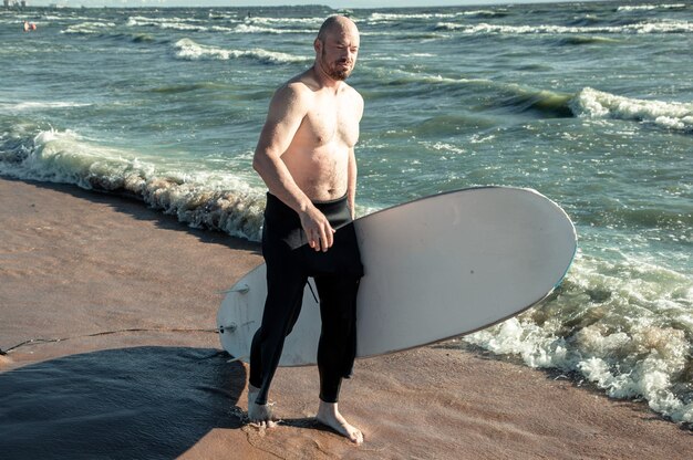 Foto vista de um surfista careca emergindo do mar