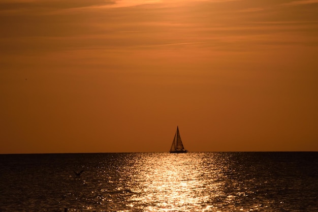 Foto vista de um veleiro no mar durante o pôr do sol