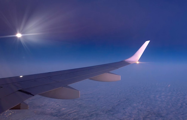 Vista de uma asa de avião em voo de dentro acima das nuvens