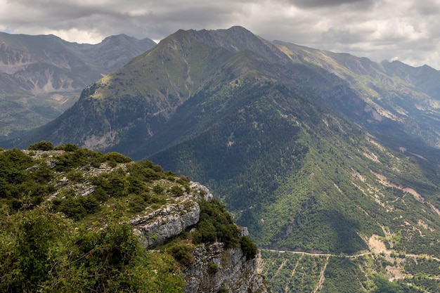 Vista de uma estrada rural e montanhas em uma região de verão nublado Tzoumerka Grécia montanhas Pindos