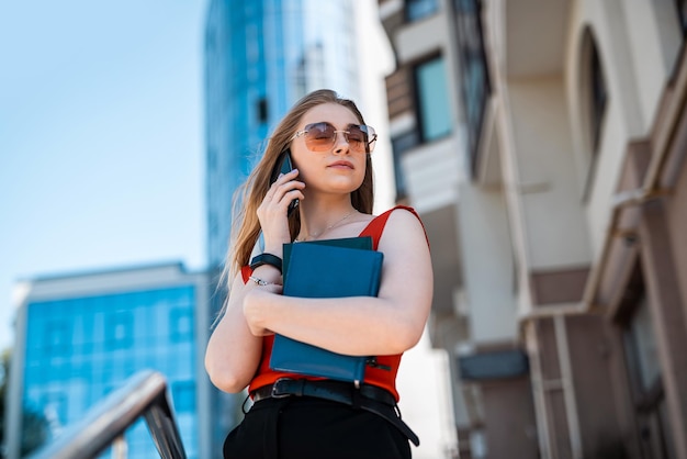 Vista de uma mulher de negócios atravessando a rua a caminho do trabalho com uma bebida de café e uma bolsa em uma área urbana da cidade Conceito de mulher de negócios Retrato de uma mulher com documentos