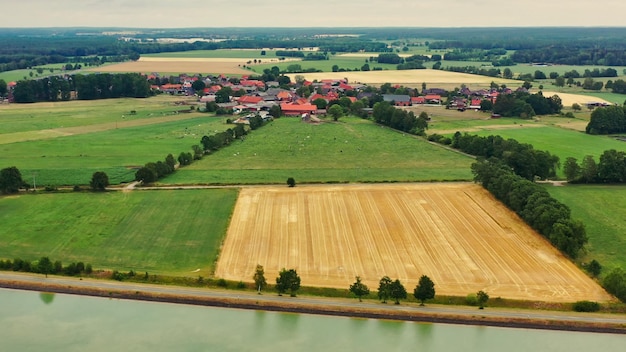 Vista de uma pequena aldeia alemã atrás de um canal na área plana, norte da Alemanha com pastagens