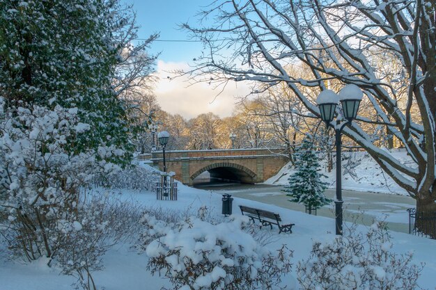 Vista de uma pequena ponte de tijolos sobre um canal congelado no centro da cidade no inverno há neve