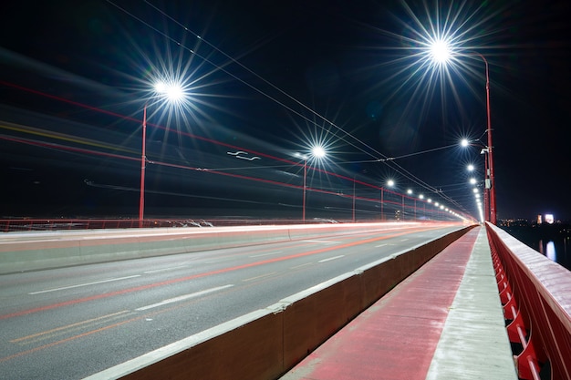 Vista de uma ponte longa e brilhante com luzes frias e carros velozes sobre o grande e belo rio dnieper em dnepropetrovsk na ucrânia