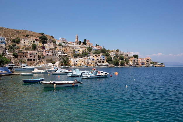 Vista de uma rua costeira e barcos de pesca ancorados no porto de Yialos, na ilha de Symi, Grécia