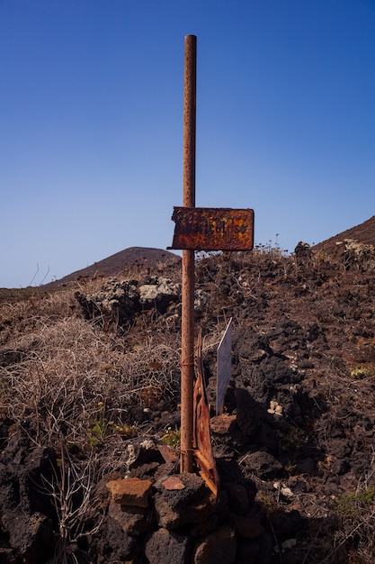 Vista de uma velha sinalização enferrujada na colina de lava, Linosa. Sicily