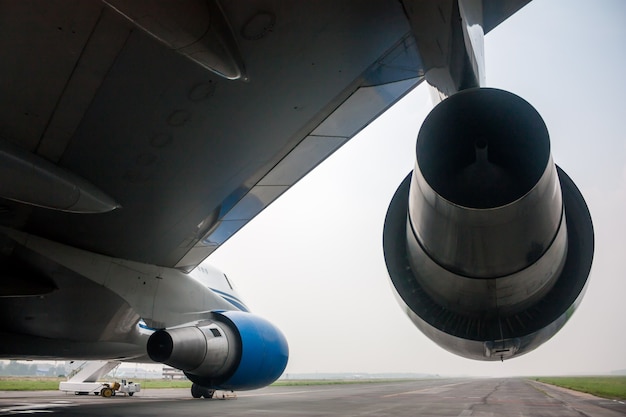 Foto vista desde debajo del ala de un gran avión de fuselaje ancho en la pista del aeropuerto