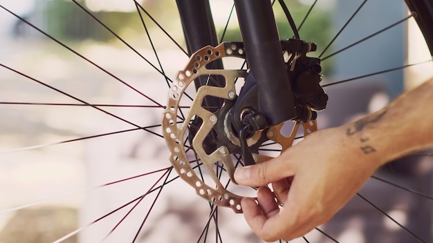 Vista detallada de una persona caucásica que separa el neumático de la horquilla delantera de la bicicleta para el mantenimiento anual. Hombre sano desmantelando rueda de bicicleta dañada para repararla con una herramienta de trabajo experta para andar en bicicleta. Fotografía de cerca.