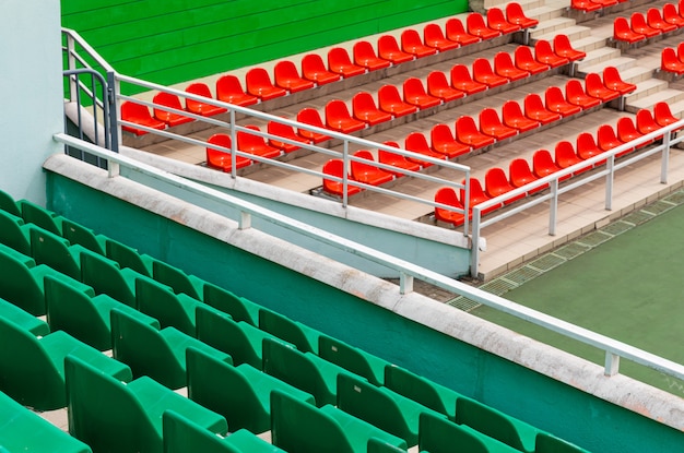 Vista diagonal do local da competição com assentos de espectadores em verde e laranja