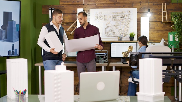 Vista de diapositiva de la transición de enfoque con arquitectos con planos. La construcción de modelos.