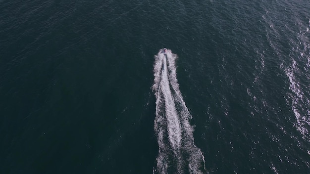 Vista dinâmica aérea da scooter de água ou embarcação pessoal ou corrida de jato de esqui através das ondas do mar