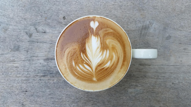 Vista directamente por encima del capuchino con arte de espuma en una mesa de madera
