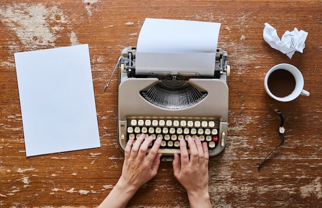 Vista directamente por encima de un hombre usando una máquina de escribir en la mesa