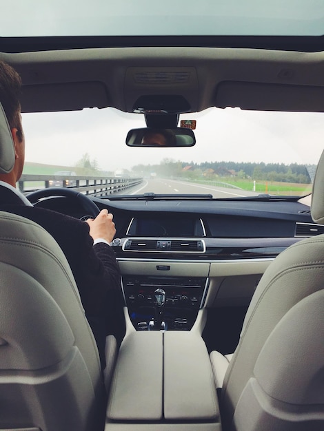 Vista do assento traseiro de um homem a conduzir um carro