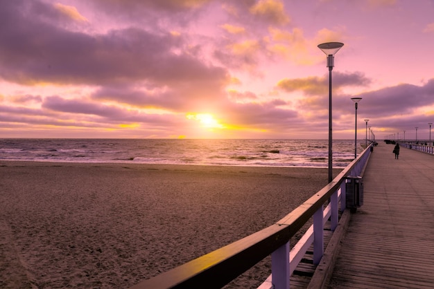 Vista do cais de madeira sobre o mar da cidade de Palanga ao pôr do sol no outono da Lituânia