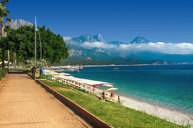 Vista do caminho e da ponte em um jardim verde com árvores verdes ao longo do aterro em Kemer Turquia