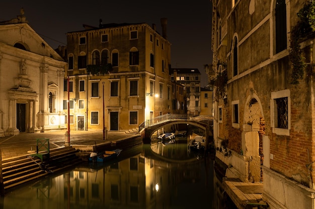 Vista do canal de Veneza à noite com ponte e edifícios históricos Itália