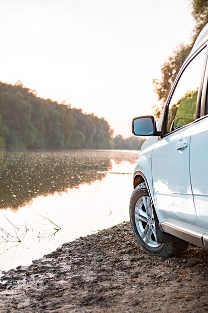 Vista do carro suv na praia fluvial no pôr do sol. copie o espaço