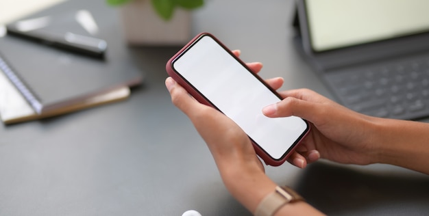 Vista do close-up da jovem empresária profissional segurando o smartphone de tela em branco