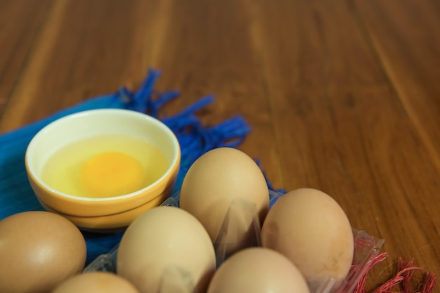 Vista do close-up de ovos de galinha crus em caixa de ovos em fundo amarelo de madeira.
