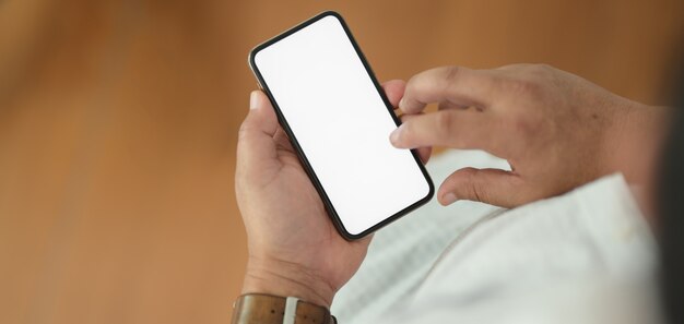Vista do close-up do homem segurando seu smartphone com escritório turva