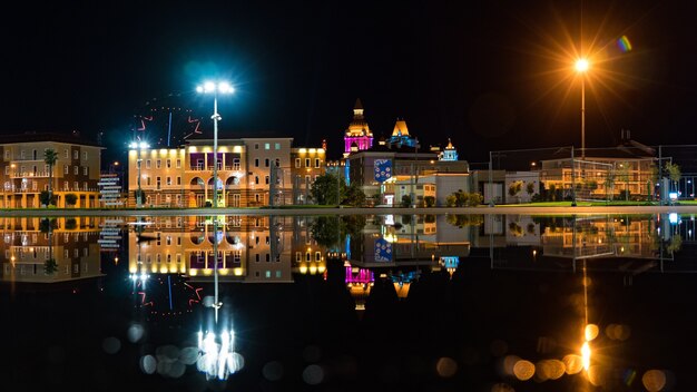 Vista do edifício iluminado à noite e reflexo na água. Parque Olímpico, Sochi, Rússia.