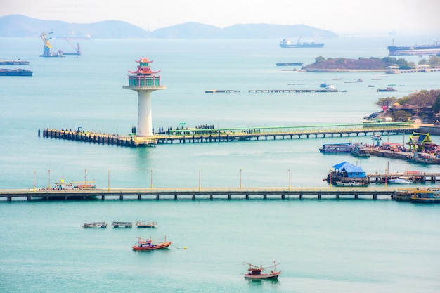 Vista do farol e do porto de Ko Sichang com navio de transporte e barco local com o mar bonito da costa leste da Tailândia.