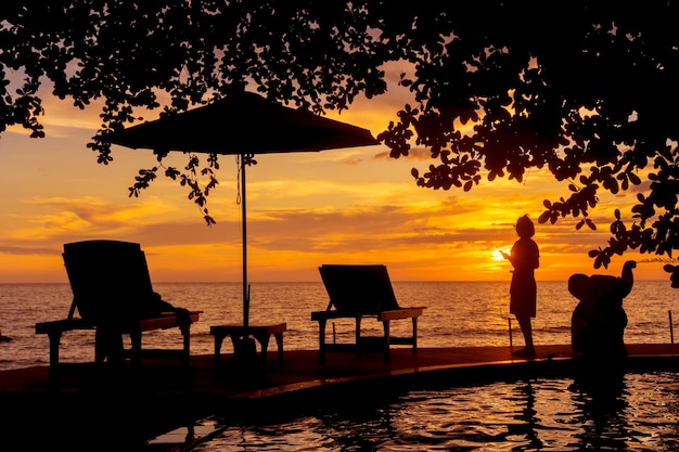 Vista do mar à noite com turistas de silhueta em pé para fotografar o pôr do solcolorfu