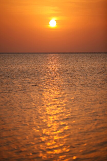 Foto vista do mar e do céu ao amanhecer sob os raios do sol dourado