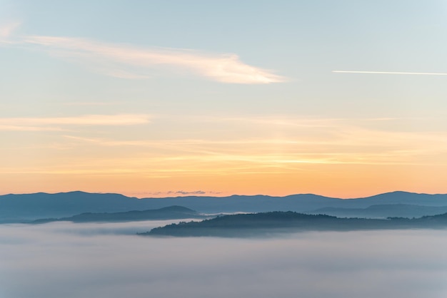 Vista do nascer do sol acima da névoa das montanhas na parte inferior