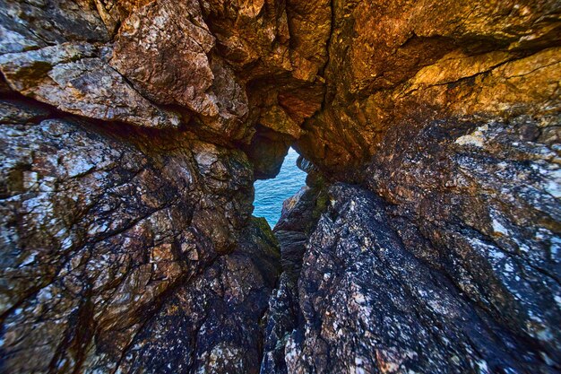 Vista do oceano através do túnel sinistro da caverna de rocha