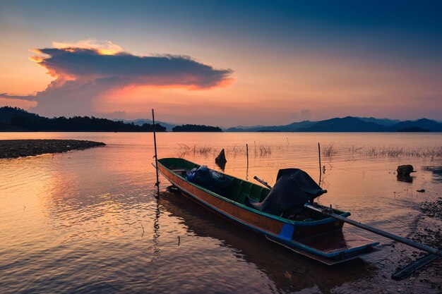 Foto vista do pôr-do-sol do reservatório de kaeng krachan com um barco de pesca e uma canoa de remo turística