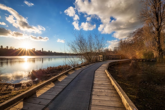 Vista do pôr do sol em um caminho de madeira em Deer Lake com Metrotown City ao fundo