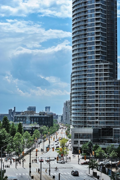 Foto vista do queens quay west em toronto, ontário. um arranha-céu contra o céu azul com nuvens brancas.