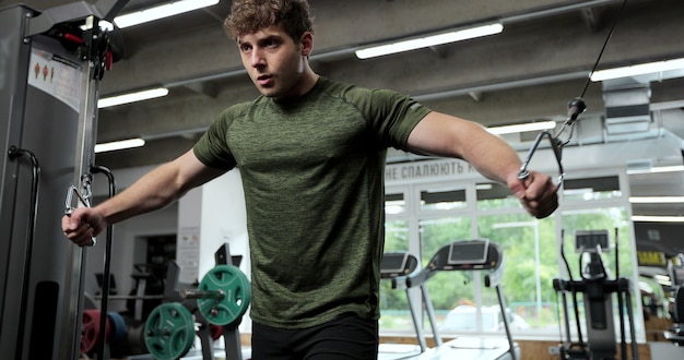 Vista do retrato dos braços de treinamento do homem com tiras de trx fitness no ginásio. homem do esporte com alças trx, passando o tempo na academia enquanto se exercita na academia.