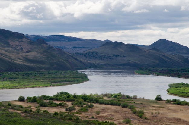 Vista do rio de uma colina alta Nas margens do rio há montanhas e colinas