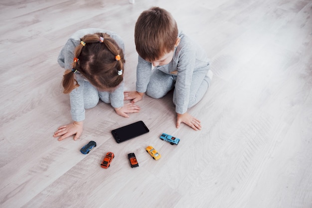 Vista do topo. Crianças usando aparelhos digitais em casa. Irmão e irmã de pijama assistem a desenhos animados e jogam em seu tablet de tecnologia.