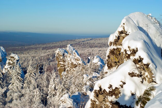 Vista do topo da cordilheira dos Urais em um dia de inverno em colinas arborizadas e rochas em primeiro plano