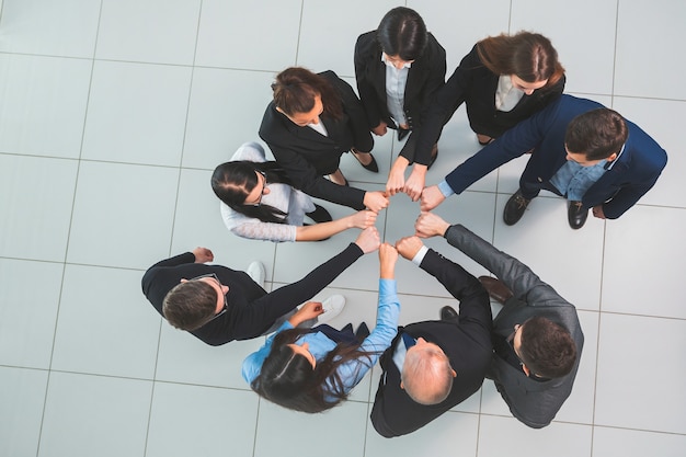 Vista do topo. grupo de jovens profissionais em um círculo. o conceito de trabalho em equipe