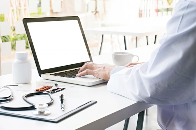 Vista dos detalhes das mãos do médico digitando no teclado com tela em branco.