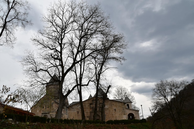 Vista dos edifícios de pedra do mosteiro. Os edifícios do mosteiro no contexto de um céu tempestuoso. Outono, árvores sem folhas.
