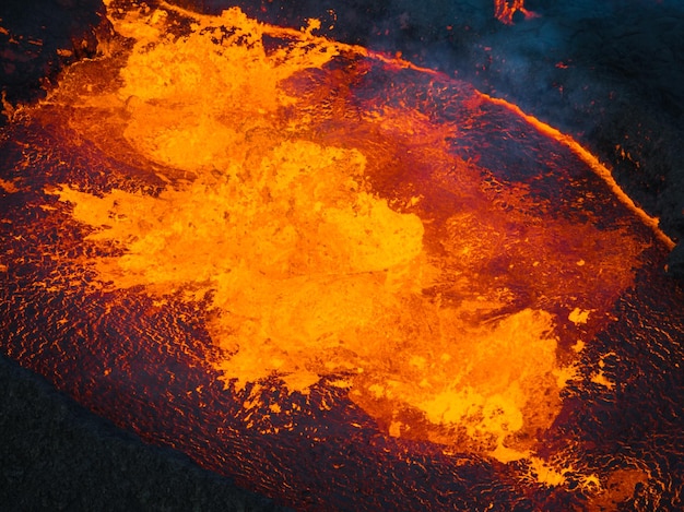 Vista dramática de paisagem vulcânica escura com lava derretida brilhante fervendo na cratera ativa