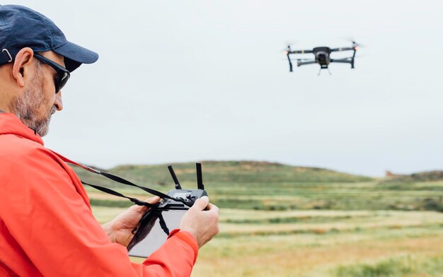 Vista de drones volando sobre un prado Controlador de drones operado por persona Grabaciones aéreas Concepto de tecnología